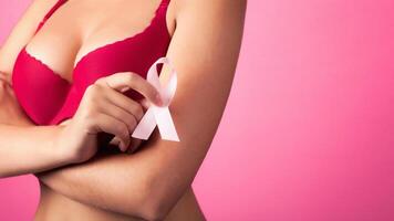 Woman with Big beautiful Breasts won Cancer. Close-up photo of a female breast in a red bra with Pink Ribbon. Background. healthcare and medicine concept