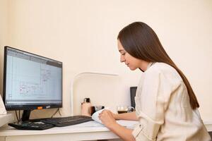 Portrait of a remote worker. An adult woman sits at a table in front of a computer and draws up a costly estimate. Confident young lady freelancer working from home. photo