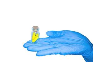 Close up of female doctor's hand in blue sterilized surgical glove holding white capsule against white background isolate photo