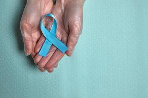 Blue cancer awareness ribbon with trail on blue background. concept of health and medicine photo