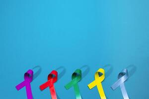 World cancer day background. Colorful ribbons, cancer awareness. blue surface from above. photo