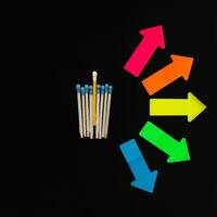 Multi-colored matches on a black background with arrows symbolizing the right to choose. Inclusion. photo