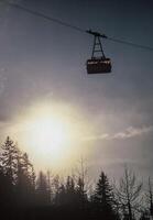 a ski lift with the sun behind it photo