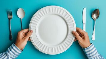 AI generated man putting empty plate with fork and spoon on blue table photo