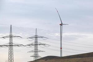 high-voltage pylons with wind turbine in german industrial landscape photo