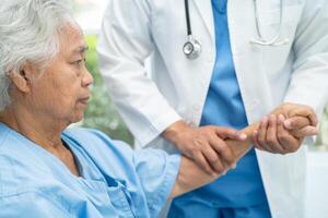 Caregiver holding hands Asian elderly woman patient with love, care, encourage and empathy at nursing hospital, healthy strong medical concept. photo