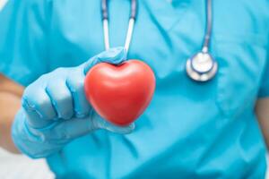 Doctor holding a red heart in hospital ward, healthy strong medical concept. photo