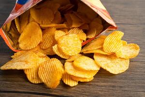 Potato chips, delicious BBQ seasoning spicy for crips, thin slice deep fried snack fast food in open bag. photo