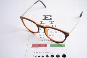 Glasses on eye testing exam chart to check eyesight accuracy of reading. photo