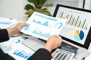 Asian accountant working and analyzing financial reports project accounting with chart graph in modern office, finance and business concept. photo