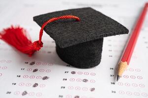 Graduation gap hat and pencil on answer sheet background, Education study testing learning teach concept. photo