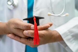 Asian doctor study learn with graduation gap hat in hospital ward, clever bright genius education medicine concept. photo