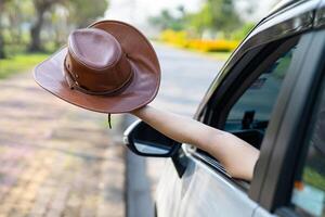 Happy enjoy and freedom in traveling trip with raised hand and holding hat outside of window car in summer vacation holiday. photo
