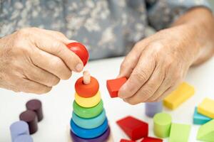 Alzheimer disease AD, Asian elderly woman patient suffering from dementia learn practical motor skills rehabilitation. photo