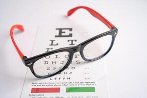 Glasses on eye testing exam chart to check eyesight accuracy of reading. photo