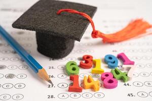 Graduation gap hat and pencil on answer sheet paper, Education study testing learning teach concept. photo