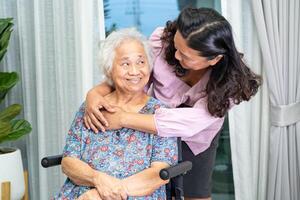 Caregiver help Asian senior woman on wheelchair with love at home. photo