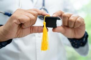 el estudio de un médico asiático aprende con un sombrero de brecha de graduación en la sala del hospital, un concepto de medicina inteligente y brillante. foto