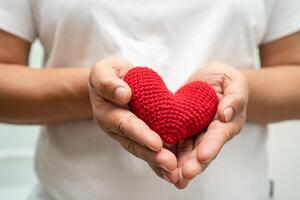 asiático mujer voluntario participación un rojo corazón, donación, caridad, confianza, seguro concepto. foto