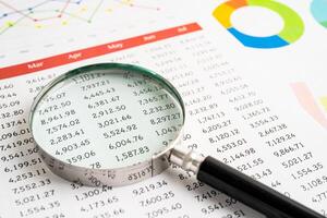 Magnifying glass on spreadsheet and graph paper. Financial development, Banking Account, Statistic, Investment Analytic research data economy, Business. photo