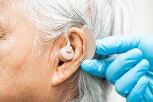 Asian senior woman patient wearing a hearing aid for treating hearing loss problem. photo