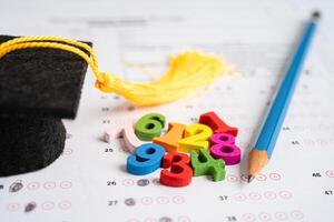 Graduation gap hat and pencil on answer sheet paper, Education study testing learning teach concept. photo