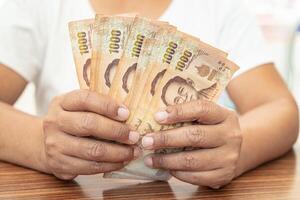 Asian business woman holding Thai banknote currency money. photo