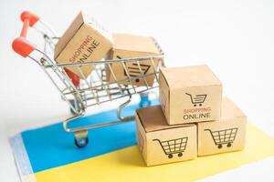 Box with shopping online cart logo and Ukraine flag, Import Export Shopping online or commerce finance delivery service store product shipping, trade, supplier concept. photo