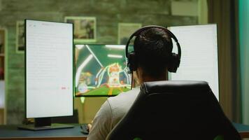 Back view of young man with hands raised celebrating victory at online shooter game. video