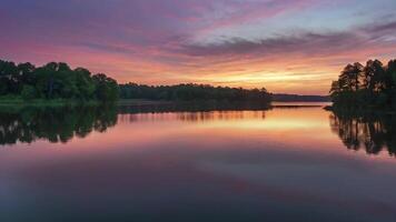 ai generato bellezza di alba rottura al di sopra di un' sereno lago, con il cielo dipinto nel tonalità di rosa e arancia video