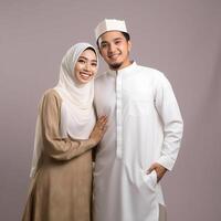 AI generated Heartwarming portrayal of a young Asian Muslim couple in traditional attire, including hijab, exchanging joyful Eid Mubarak gestures in a studio setting with a neutral color palette photo