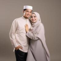 AI generated Heartwarming portrayal of a young Asian Muslim couple in traditional attire, including hijab, exchanging joyful Eid Mubarak gestures in a studio setting with a neutral color palette photo
