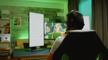 Young man with headphones talking on chat while playing shooter games on powerful PC video