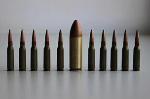 A line of identical regular caliber bullets with one huge large caliber bullet front view detailed stock photo