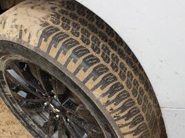 Tread blocks of car tire covered by sand after extreme off road adventure photo