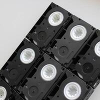 Black block made by rows of old small tape video cassettes on white surface photo