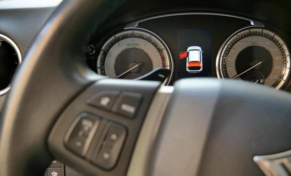 Car dashboard with illuminated open door icon behind defocused steering wheel photo