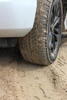 Sand on the tire tread of front wheel of the car on a sandy ground road photo