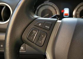 Steering Wheel With Control Buttons In Front Of Defocused Activated Open Door Safety Sign On A Car Dashboard photo