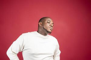 Young African American man thinking and looking up, on red background photo