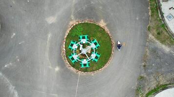 Aerial view of a person riding a motorbike near an urban roundabout, showcasing everyday city life from above and the concept of life circle video