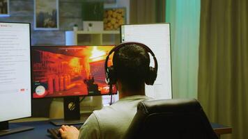 indietro Visualizza di professionista gamer festeggiare il suo vittoria mentre giocando in linea tiratore gioco su potente pc. gioco streaming. video