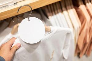 blank tag with Clothes hang on a shelf in a designer clothes store. Clothing hanging on a clothing rack in a store photo