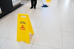 Yellow Caution slippery wet floor sign on the wet ground photo