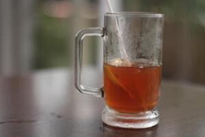 un vaso de con hielo limón té en el mesa. refrescante con hielo té con limón, a el cafetería. foto