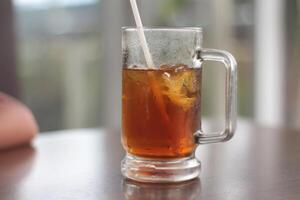 un vaso de con hielo limón té en el mesa. refrescante con hielo té con limón, a el cafetería. foto