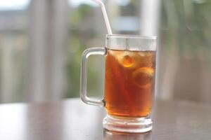 un vaso de con hielo limón té en el mesa. refrescante con hielo té con limón, a el cafetería. foto