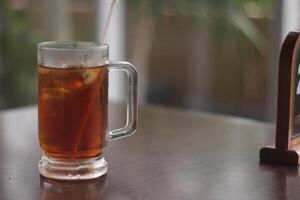 un vaso de con hielo limón té en el mesa. refrescante con hielo té con limón, a el cafetería. foto