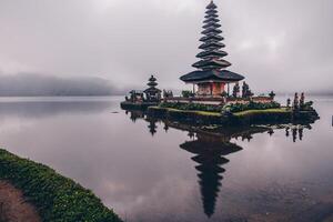 reflexión en el nublado día de pura ulan danu bratan un famoso pintoresco punto de referencia y un significativo templo en el costas de lago bratan en bali, Indonesia. foto