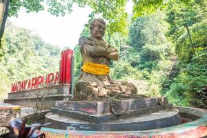 East Java, Indonesia - 19 July 2018 - The statue of Gajah Mada the powerful military leader of Majapahit empire located at the entrance way to Madakaripura waterfalls the tallest waterfalls in Java. photo